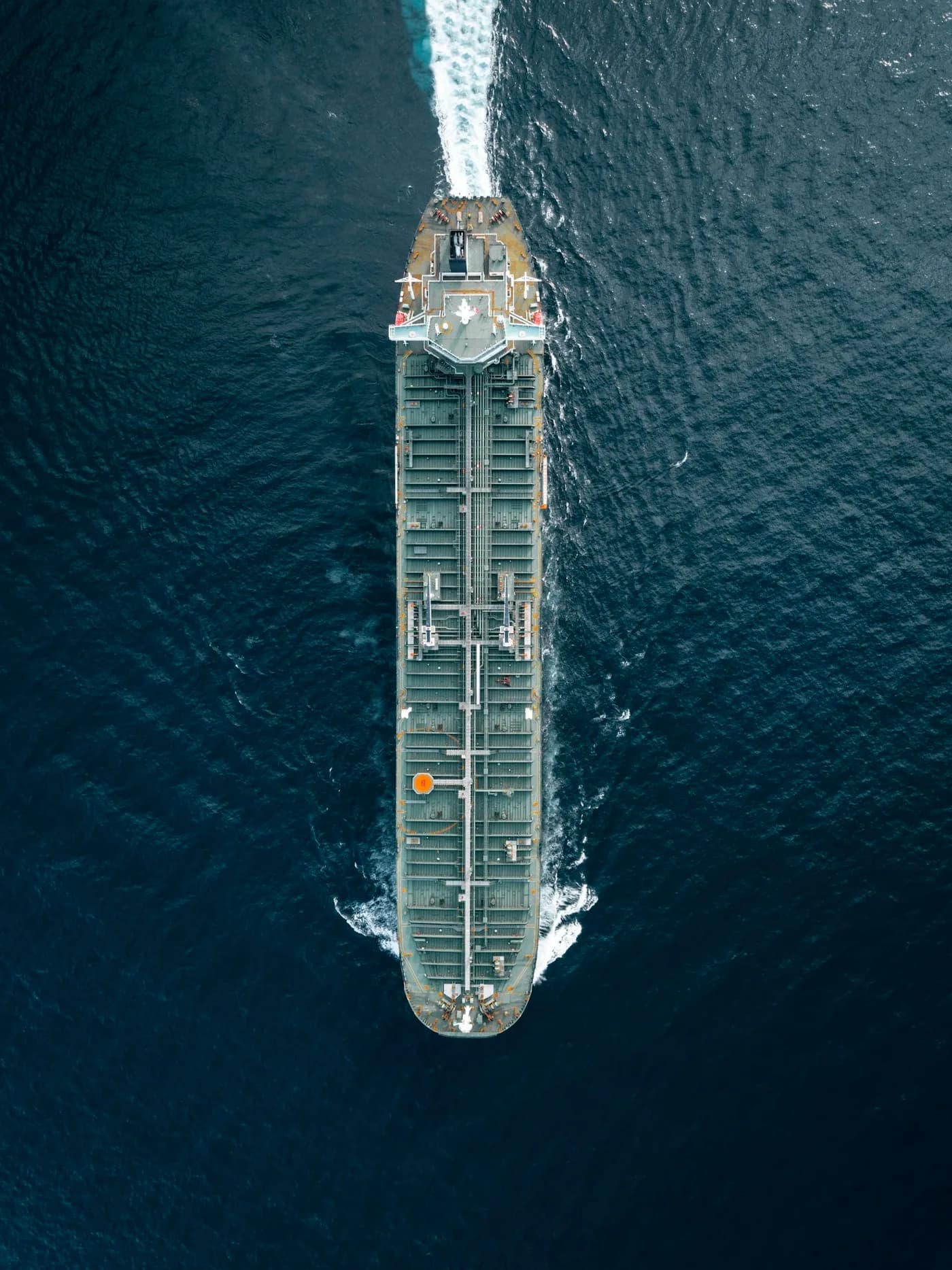 A bulk carrier crossing deep blue ocean waters, seen from above